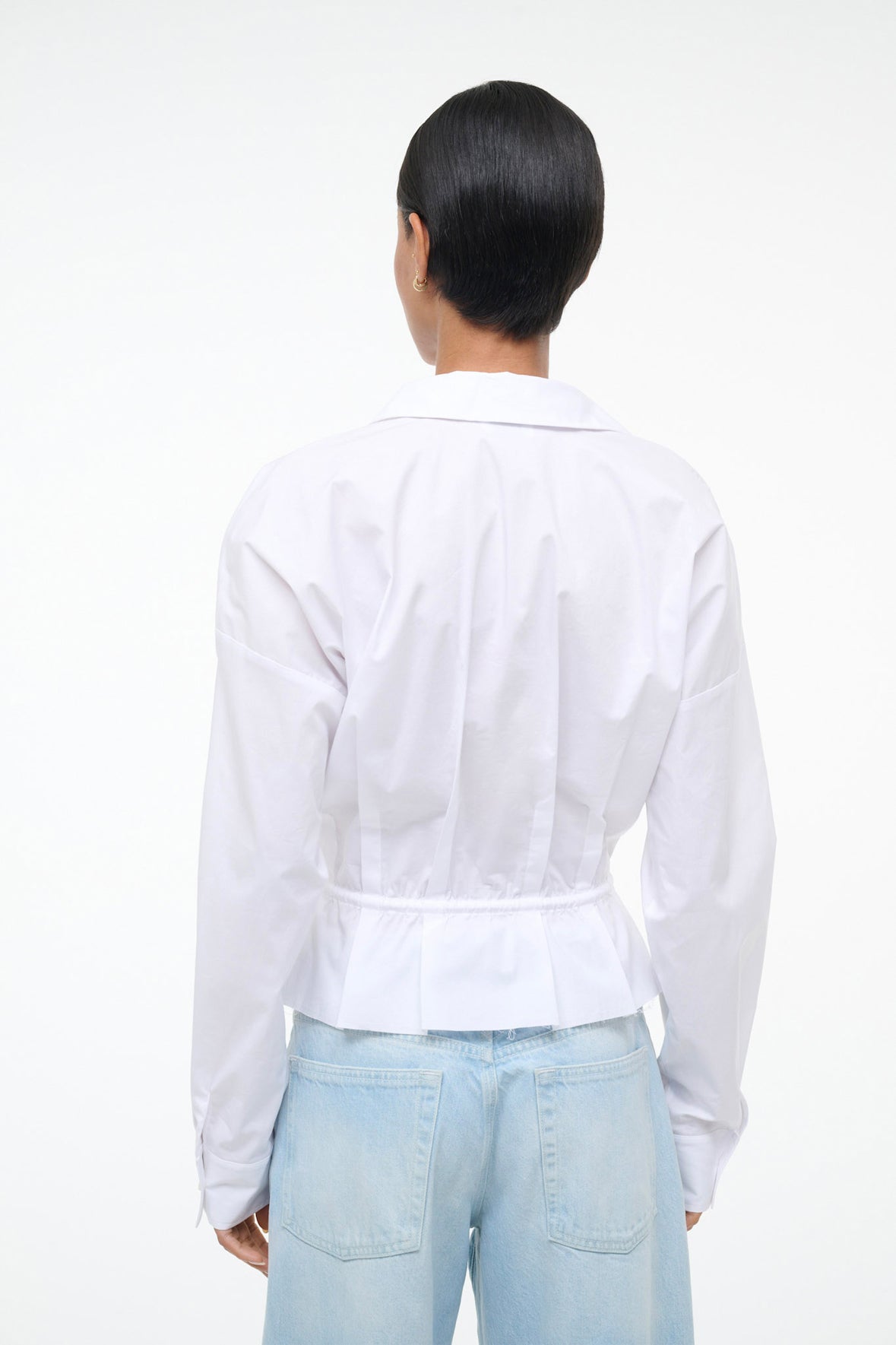 Person wearing a white shirt and light blue jeans on a white background