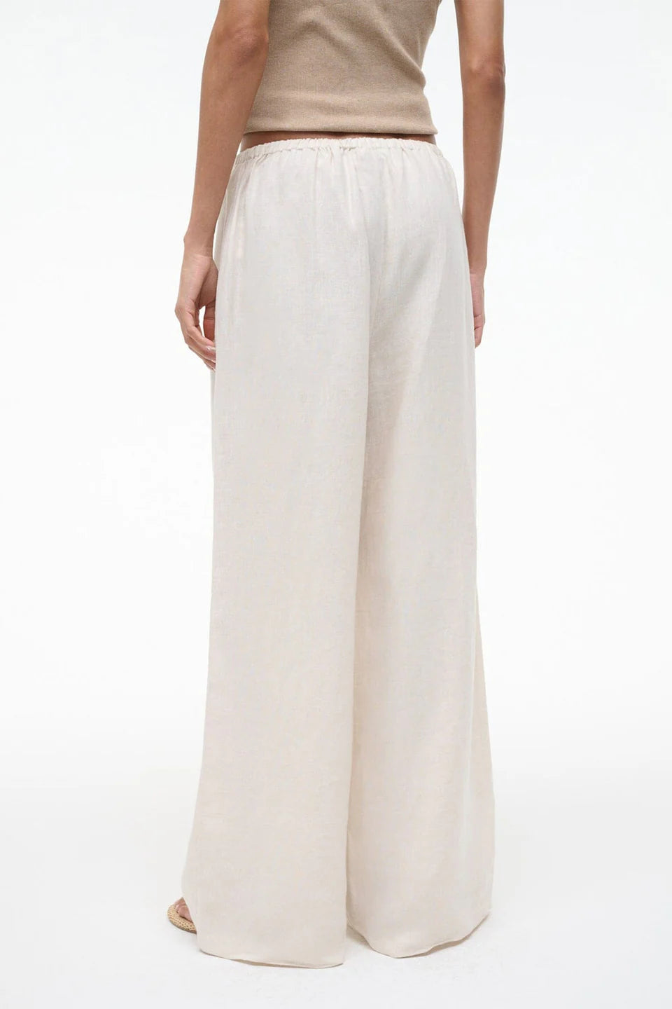 Person wearing white wide-leg pants on a white background
