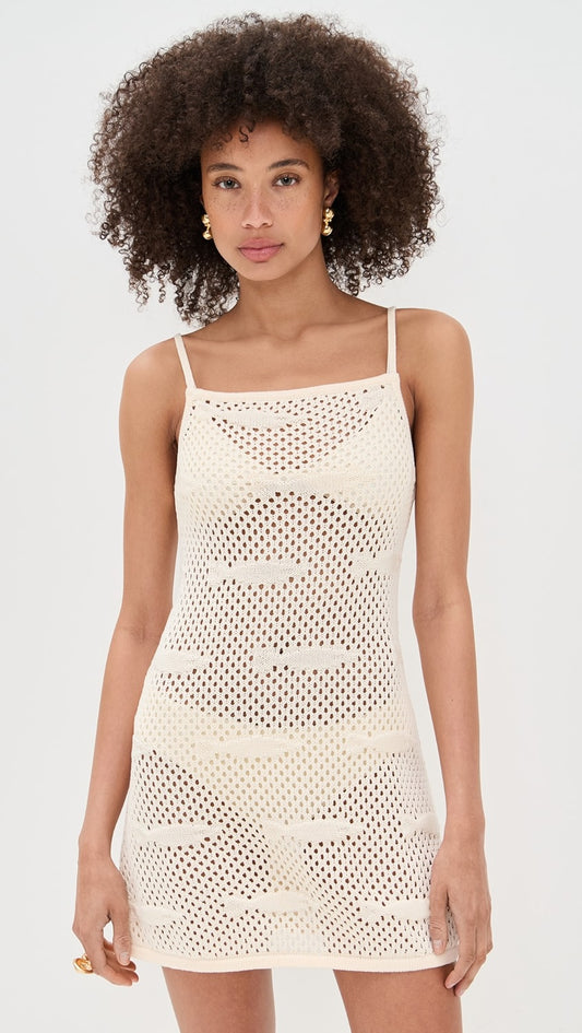 Woman wearing a beige crochet dress against a white background