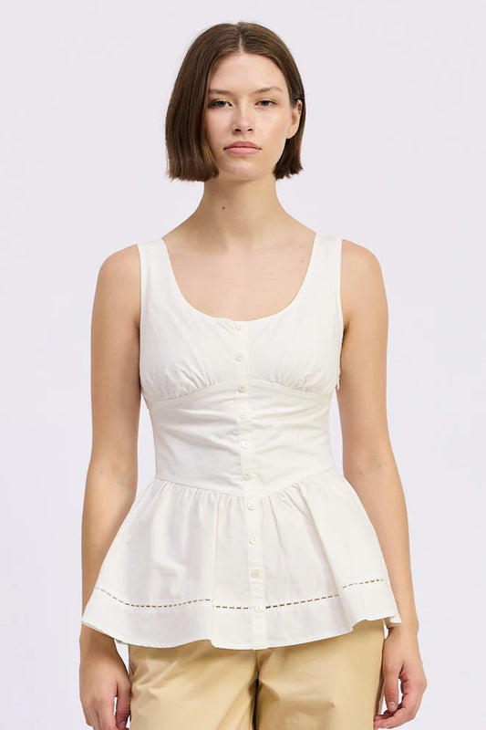 Woman wearing a white sleeveless top with a plain background