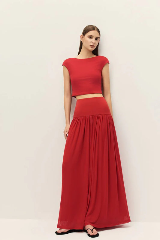 Woman wearing a red outfit with a top and long skirt on a white background