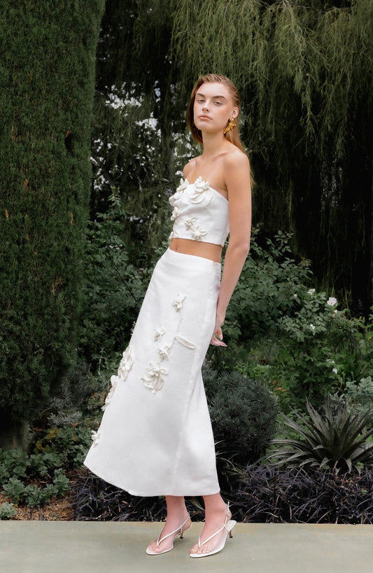 Woman in a white floral dress standing in a garden setting