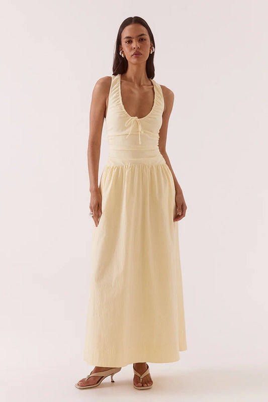 Woman wearing a light yellow sleeveless dress on a white background
