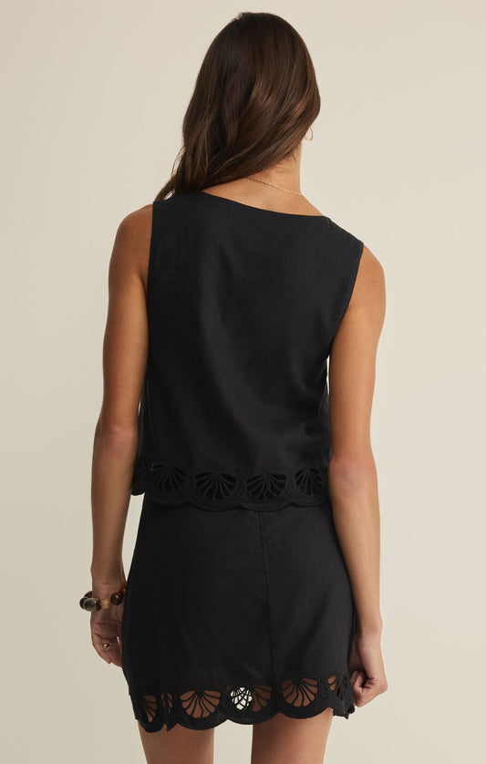Black sleeveless dress with lace details on a beige background