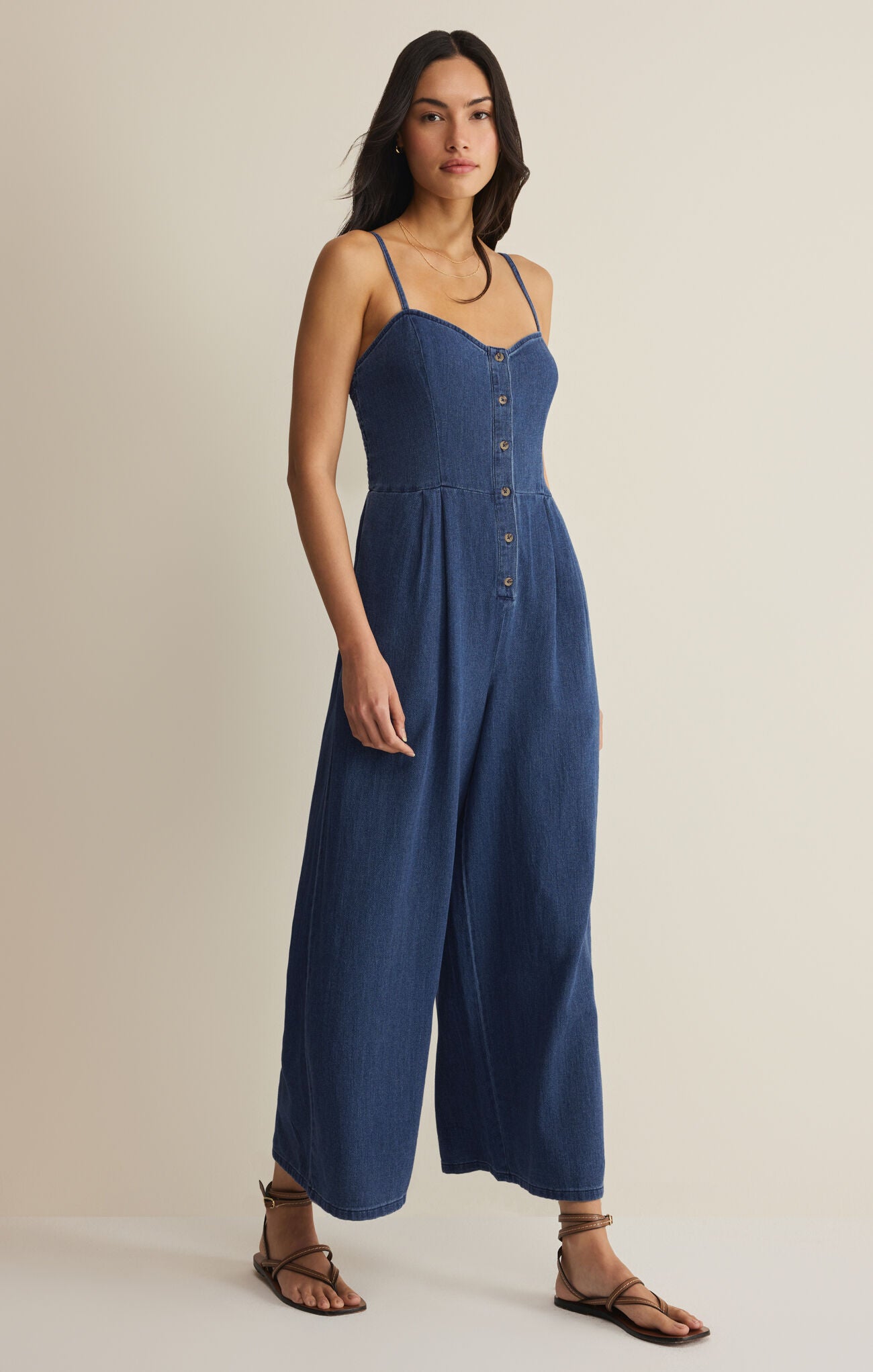 Woman wearing a blue jumpsuit on a beige background