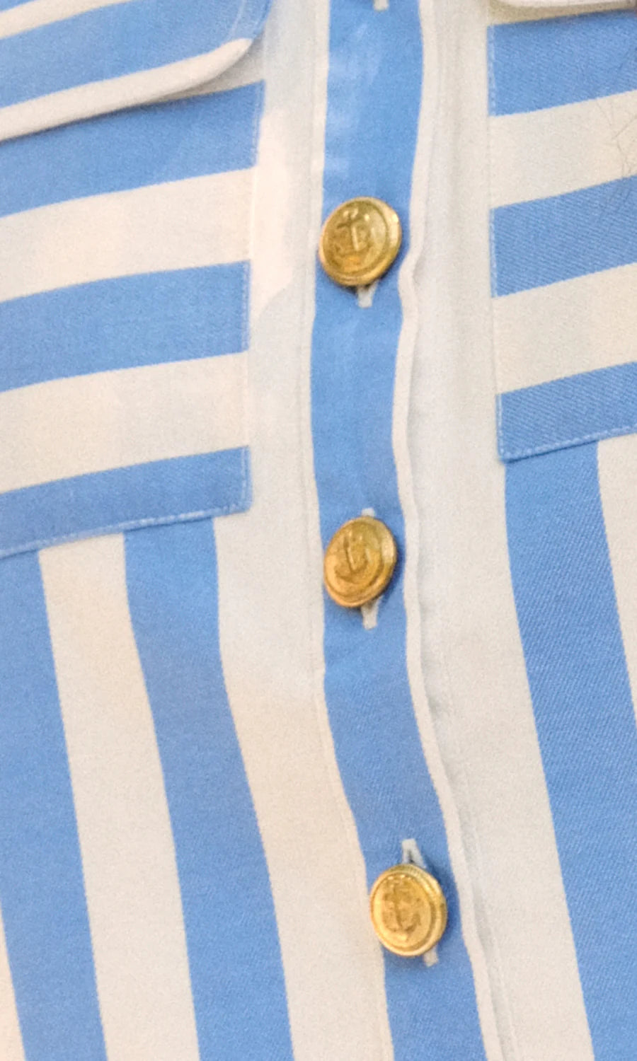 Close-up of a blue and white striped shirt with gold buttons.