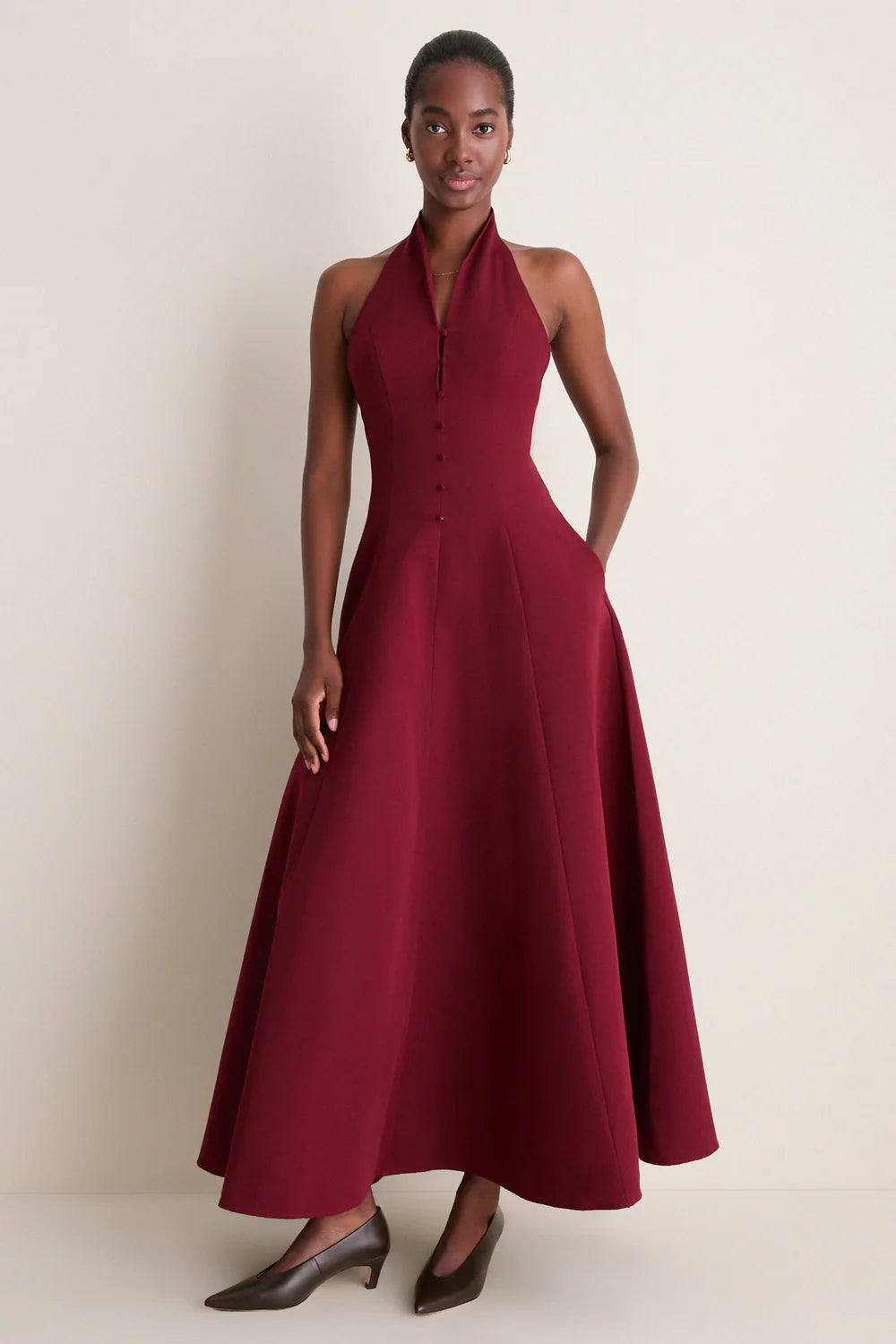 A model wearing the Staud Carmino Stella dress which features button detailing along the front and brown heels.