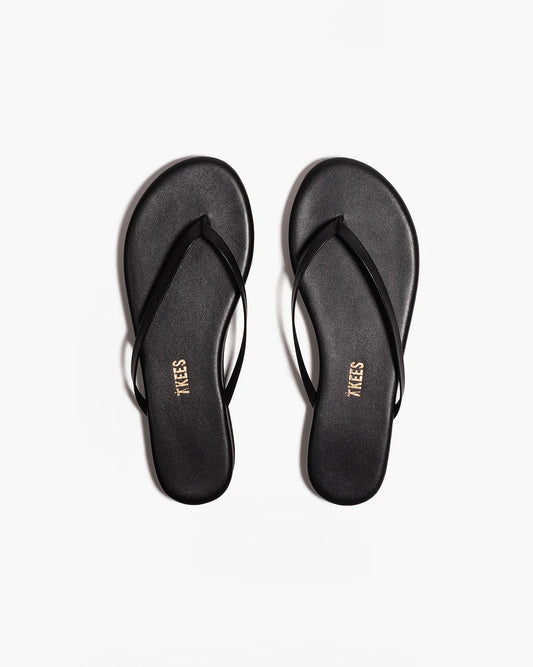 Black flip-flops with 'TIKES' branding on a white background from the top view