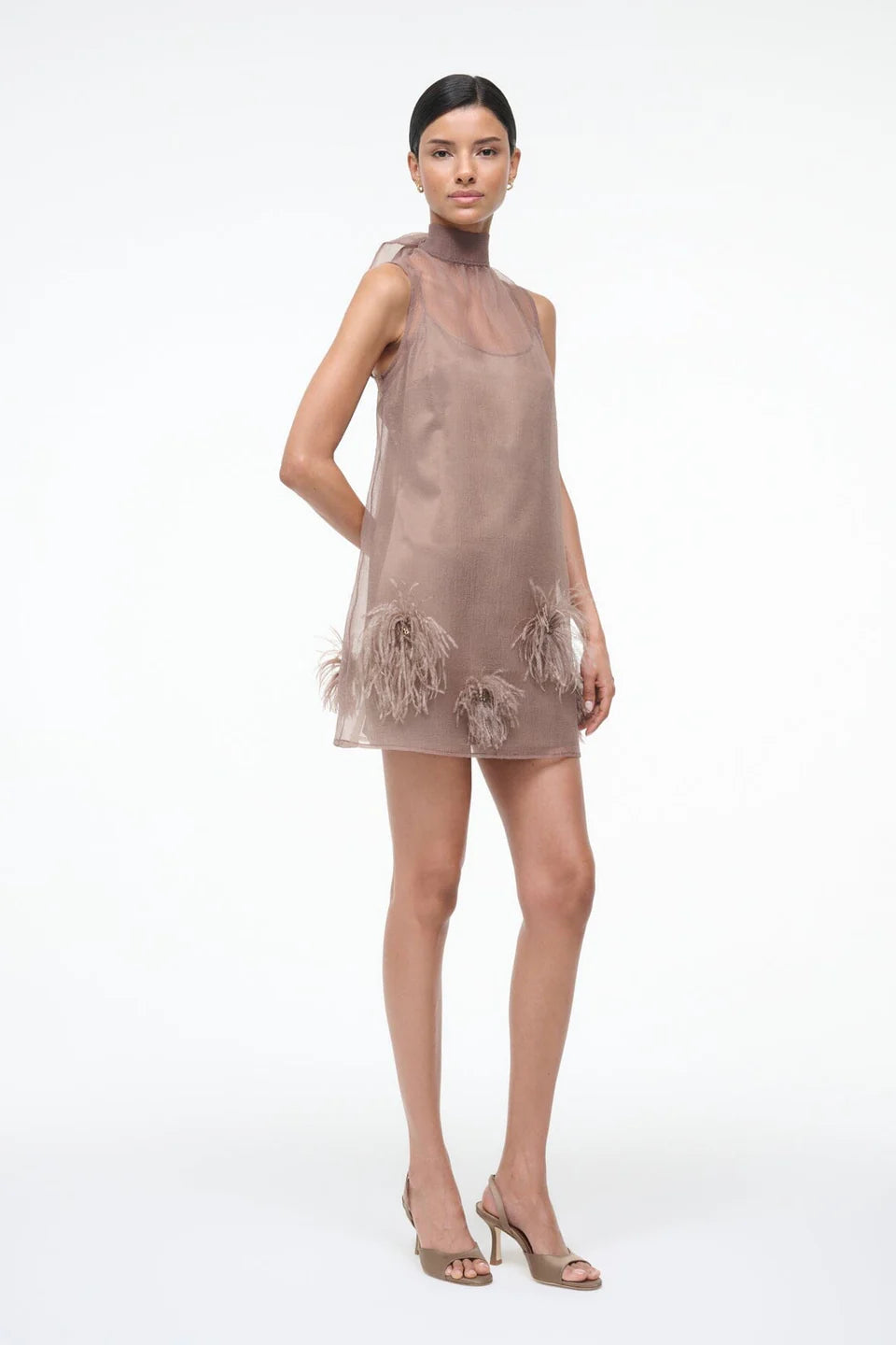 Woman wearing a beige dress with floral lace details on a white background