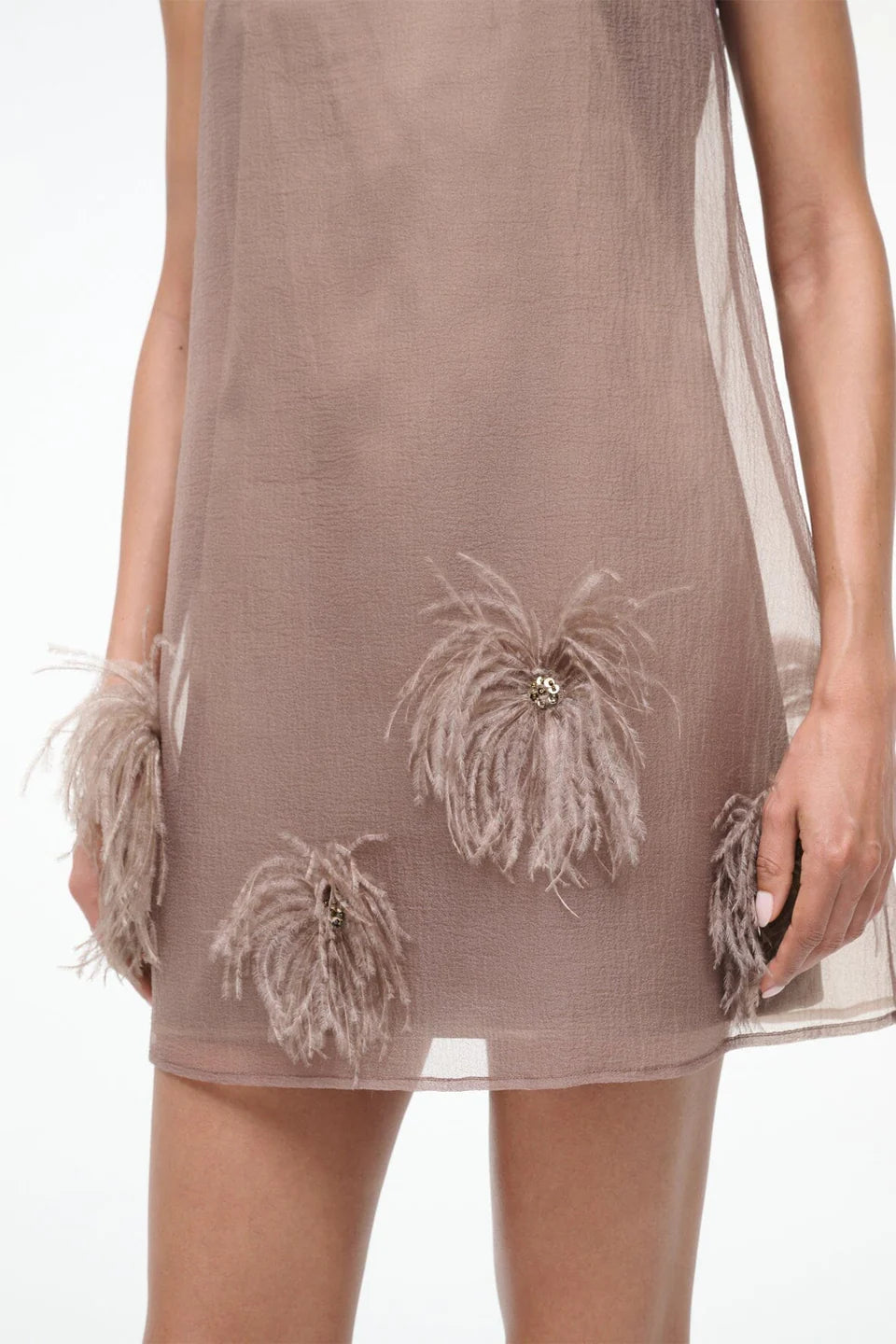 Brown dress with feather embellishments on a white background