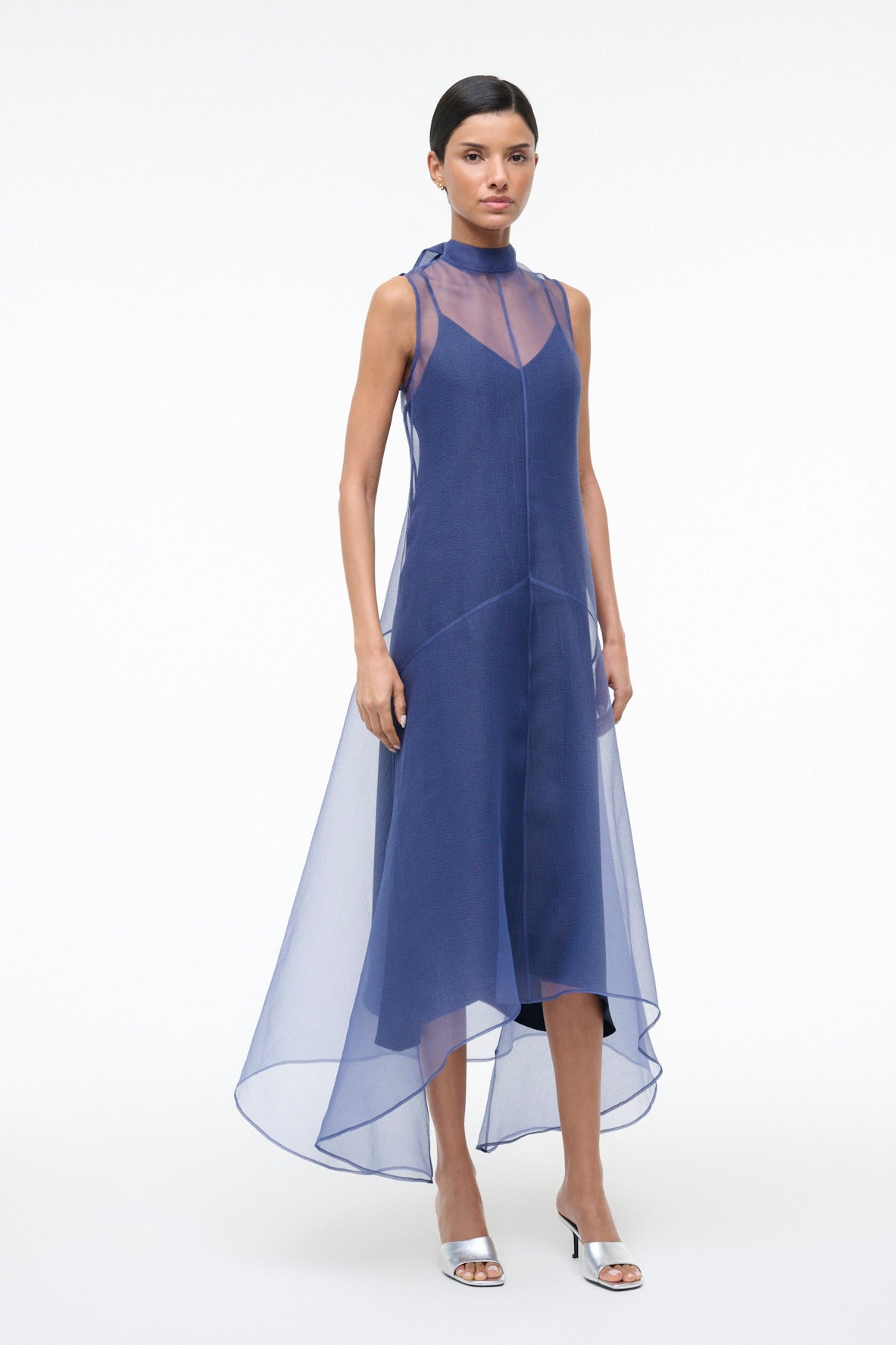 Woman wearing a blue dress with sheer panels on a white background