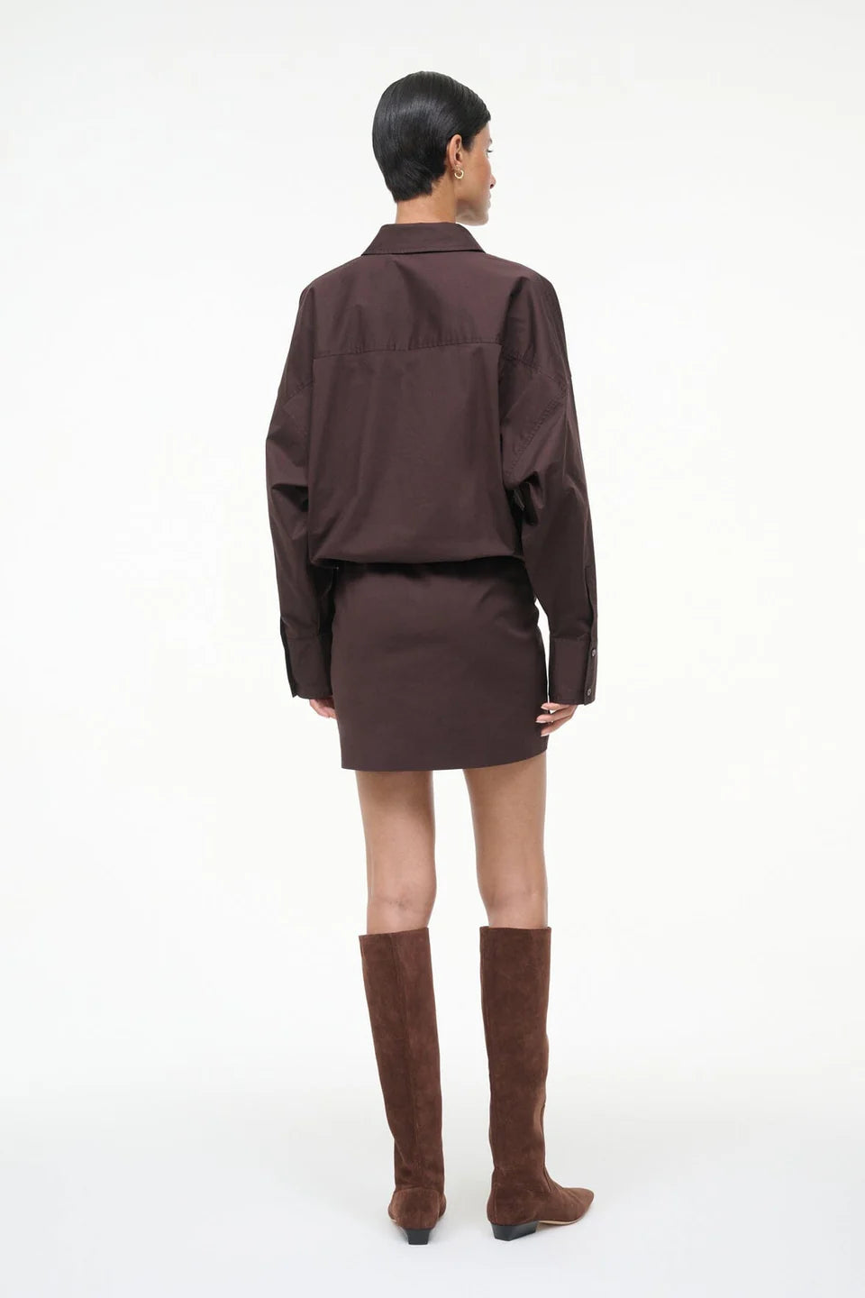 Person wearing a brown outfit with knee-high boots on a white background