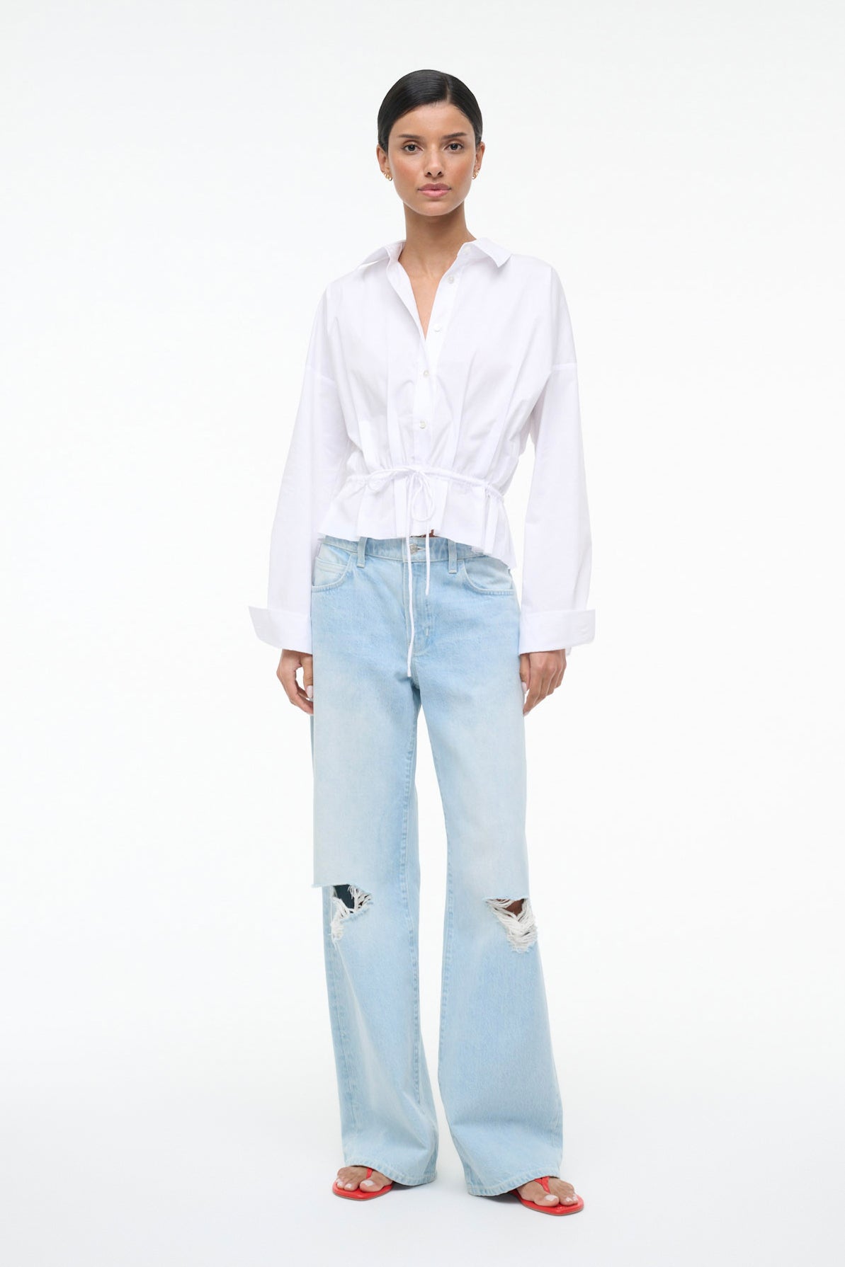 Woman wearing a white blouse and light blue jeans on a white background