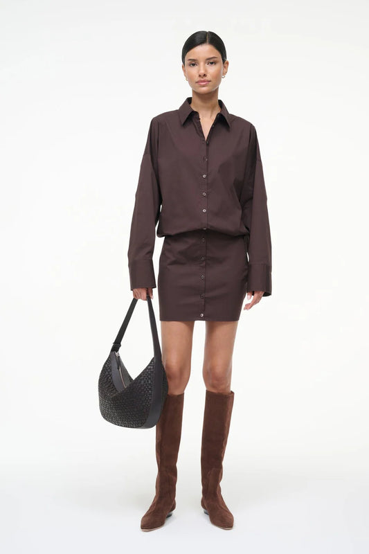 Woman wearing a brown outfit with a black bag on a white background