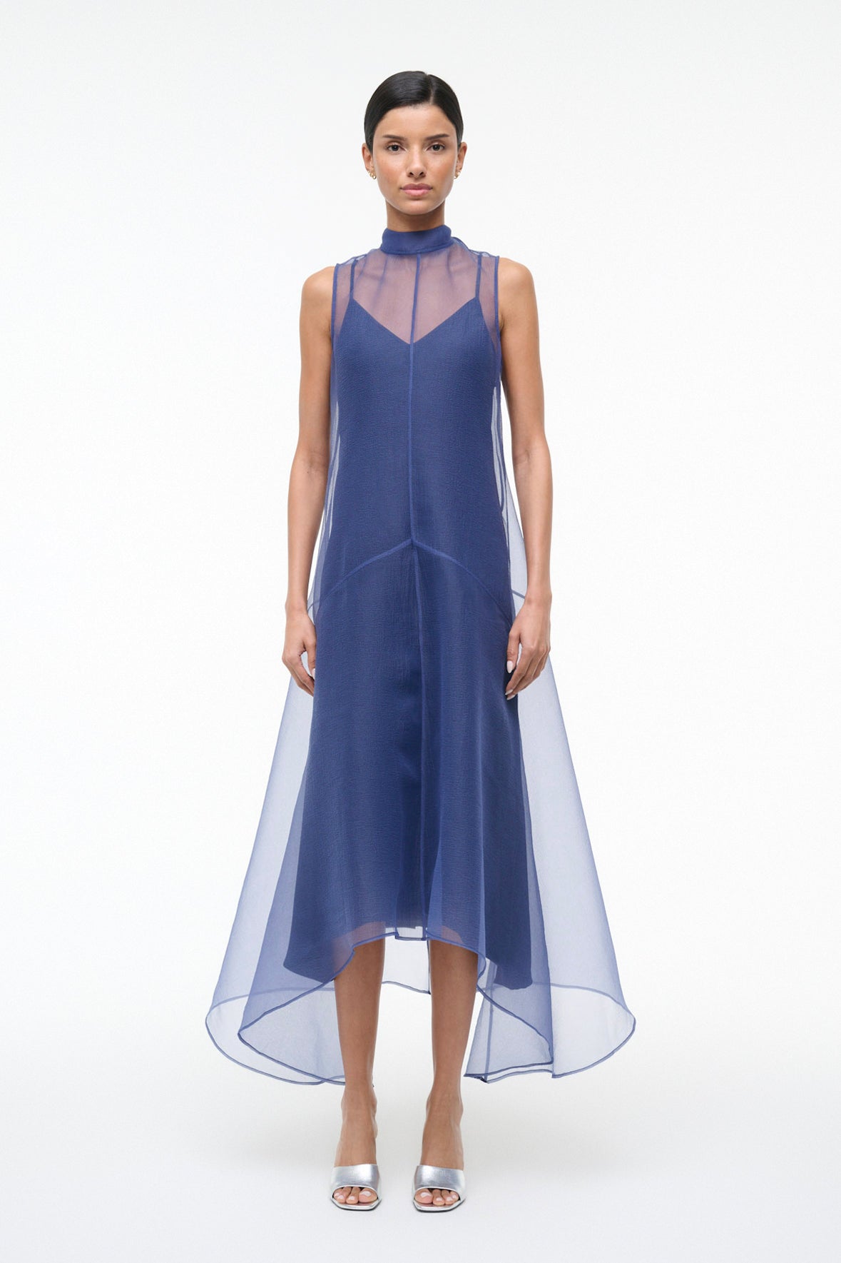 Woman wearing a blue dress with sheer overlay on a white background