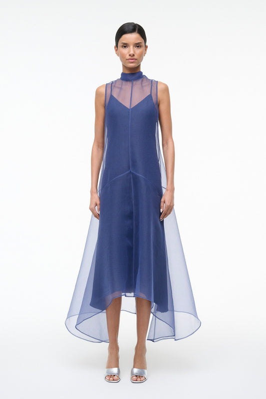 Woman wearing a blue dress with sheer overlay on a white background