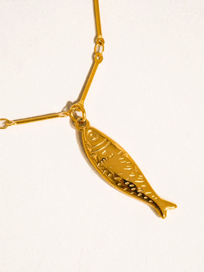 Close up of fish charm on gold necklace