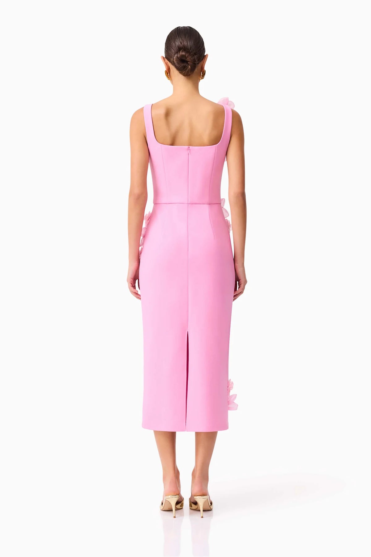 Woman wearing a pink dress with a backless design on a white background