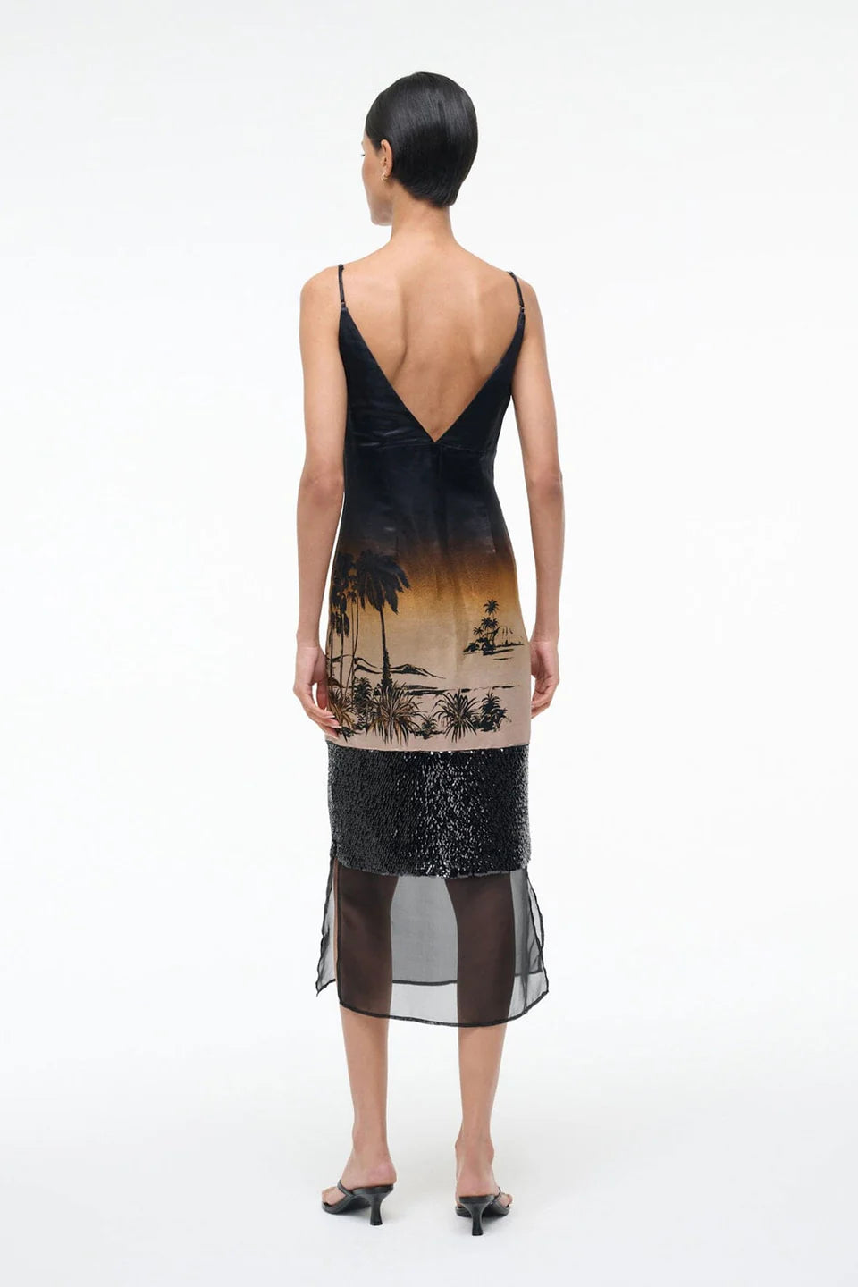 Woman wearing a black dress with a tropical print on a white background