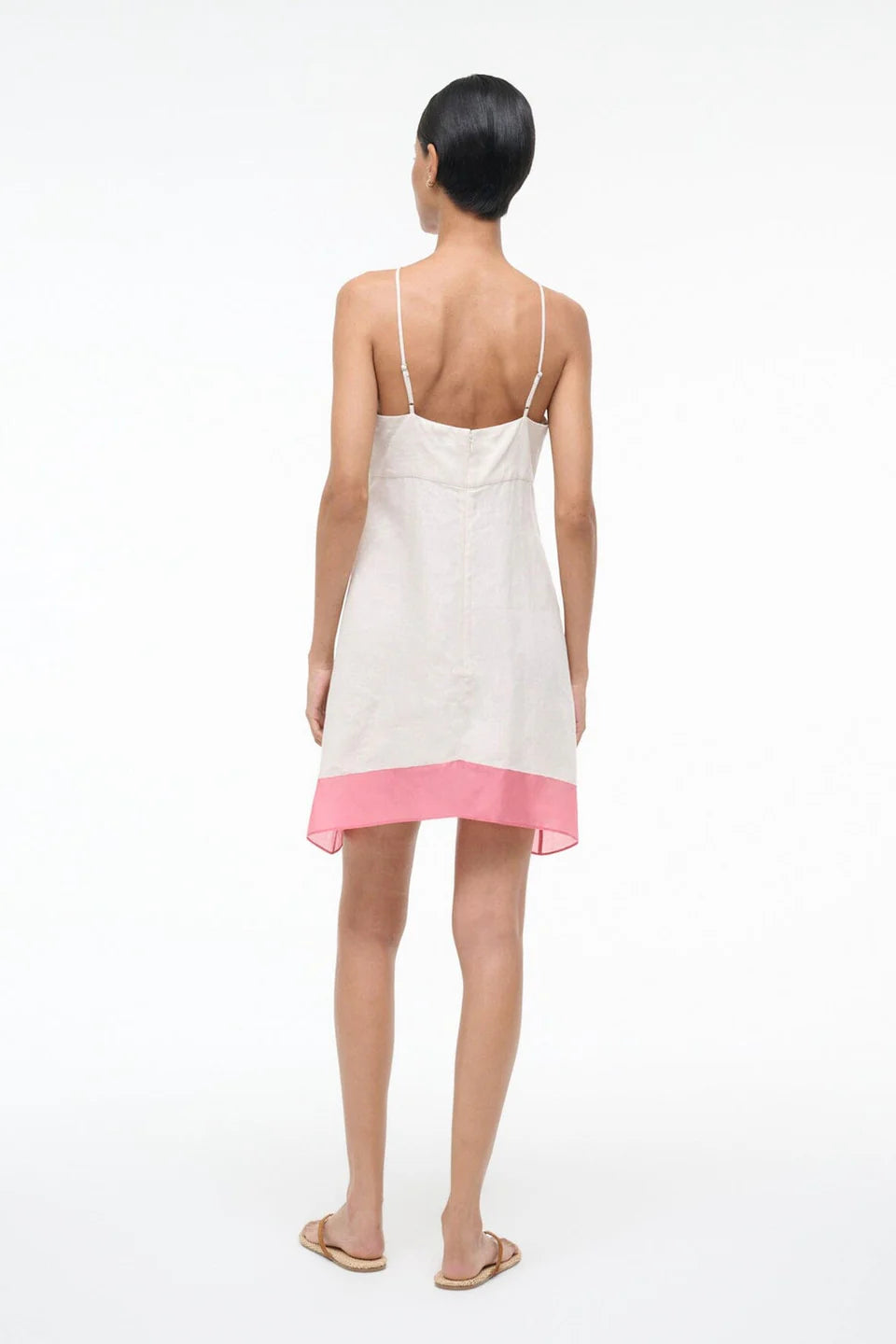 Woman wearing a white dress with a pink hem on a white background