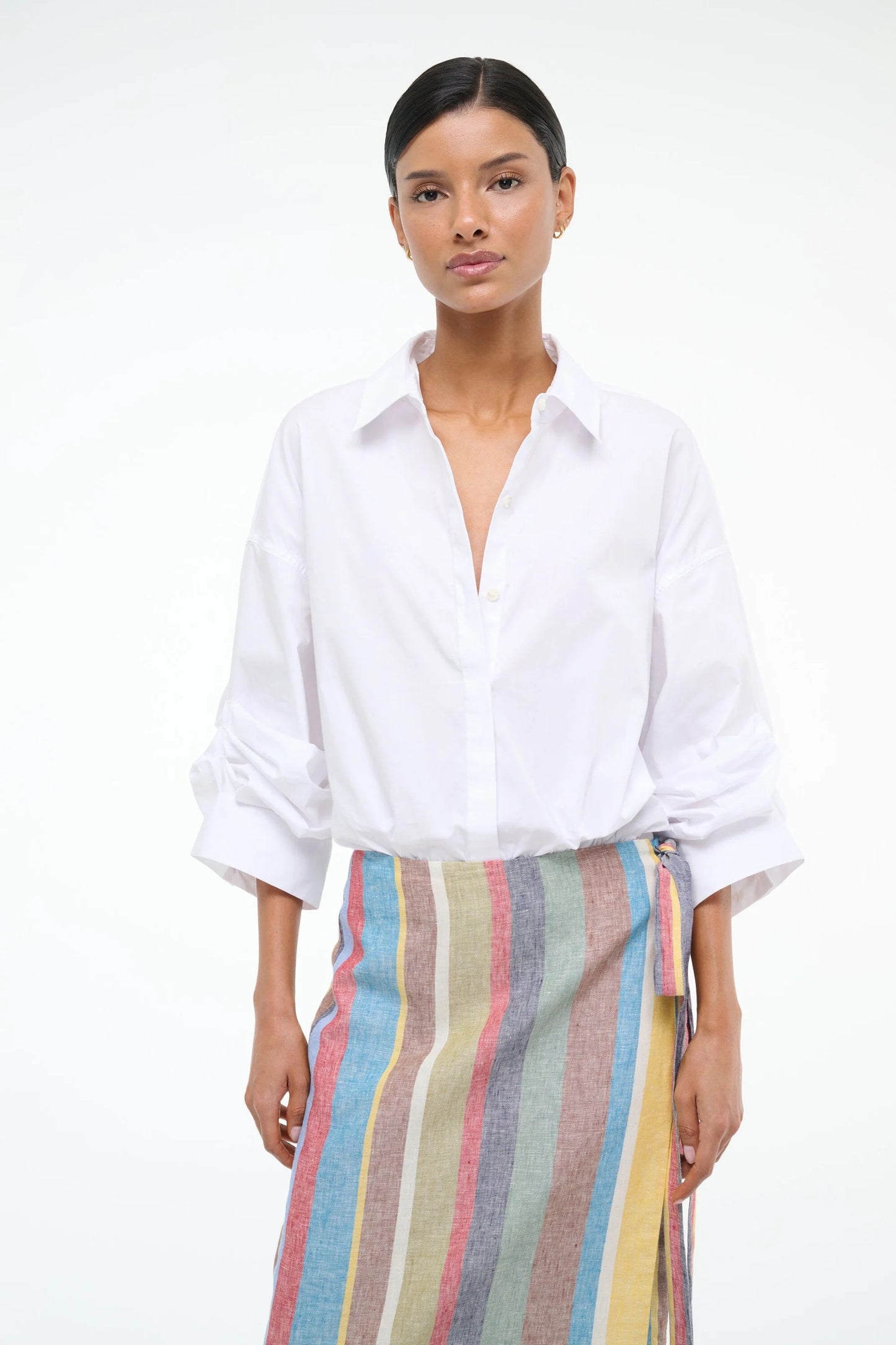 Woman wearing a white shirt and colorful striped pants on a white background