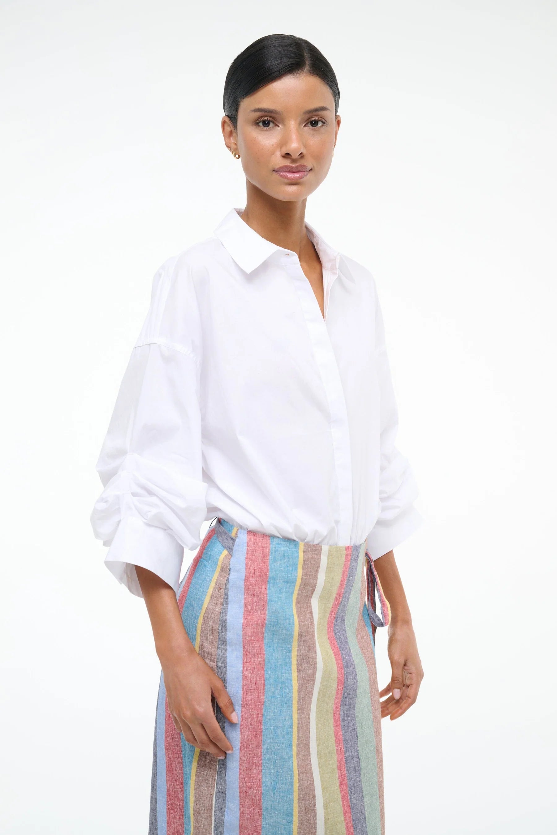 Woman wearing a white shirt and colorful striped pants on a white background