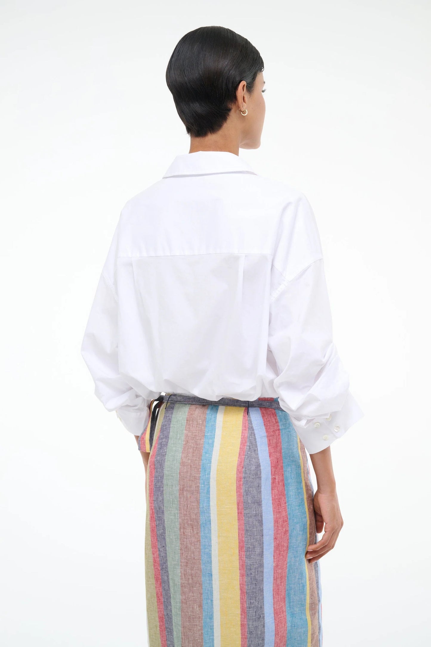 Person wearing a white shirt and colorful striped skirt on a white background