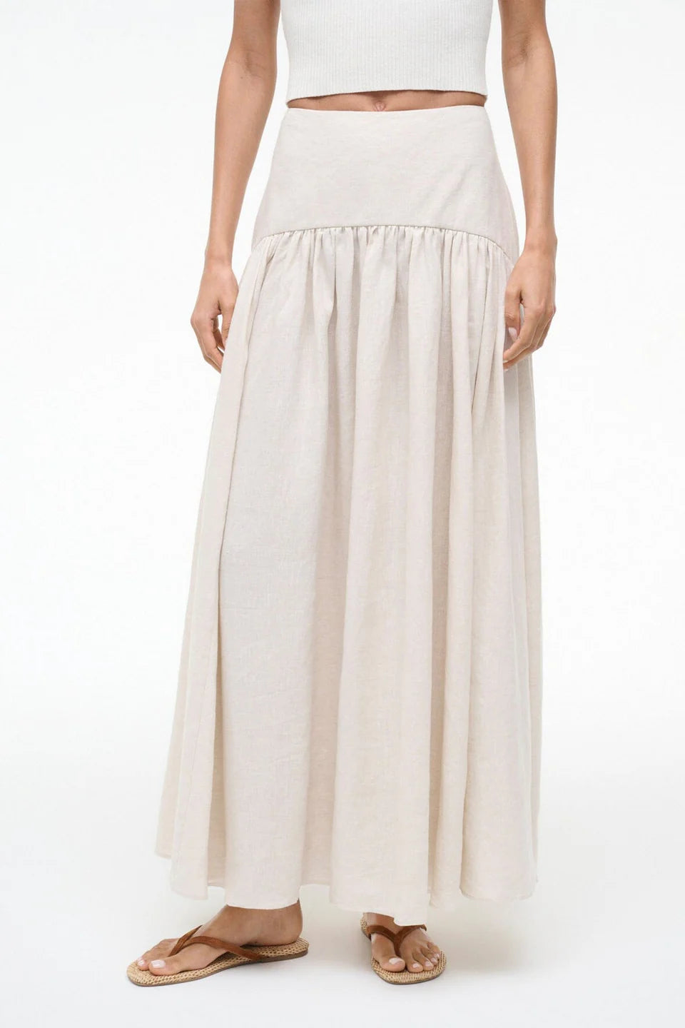 Person wearing a long beige skirt on a white background