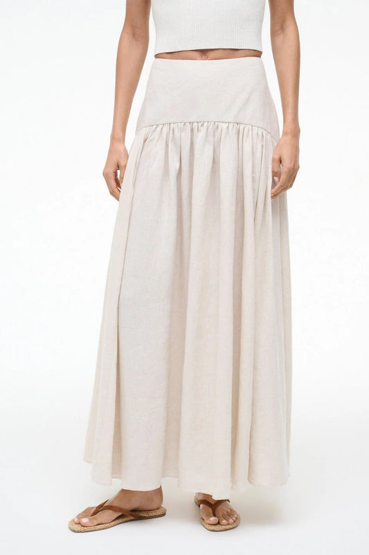 Person wearing a long beige skirt on a white background