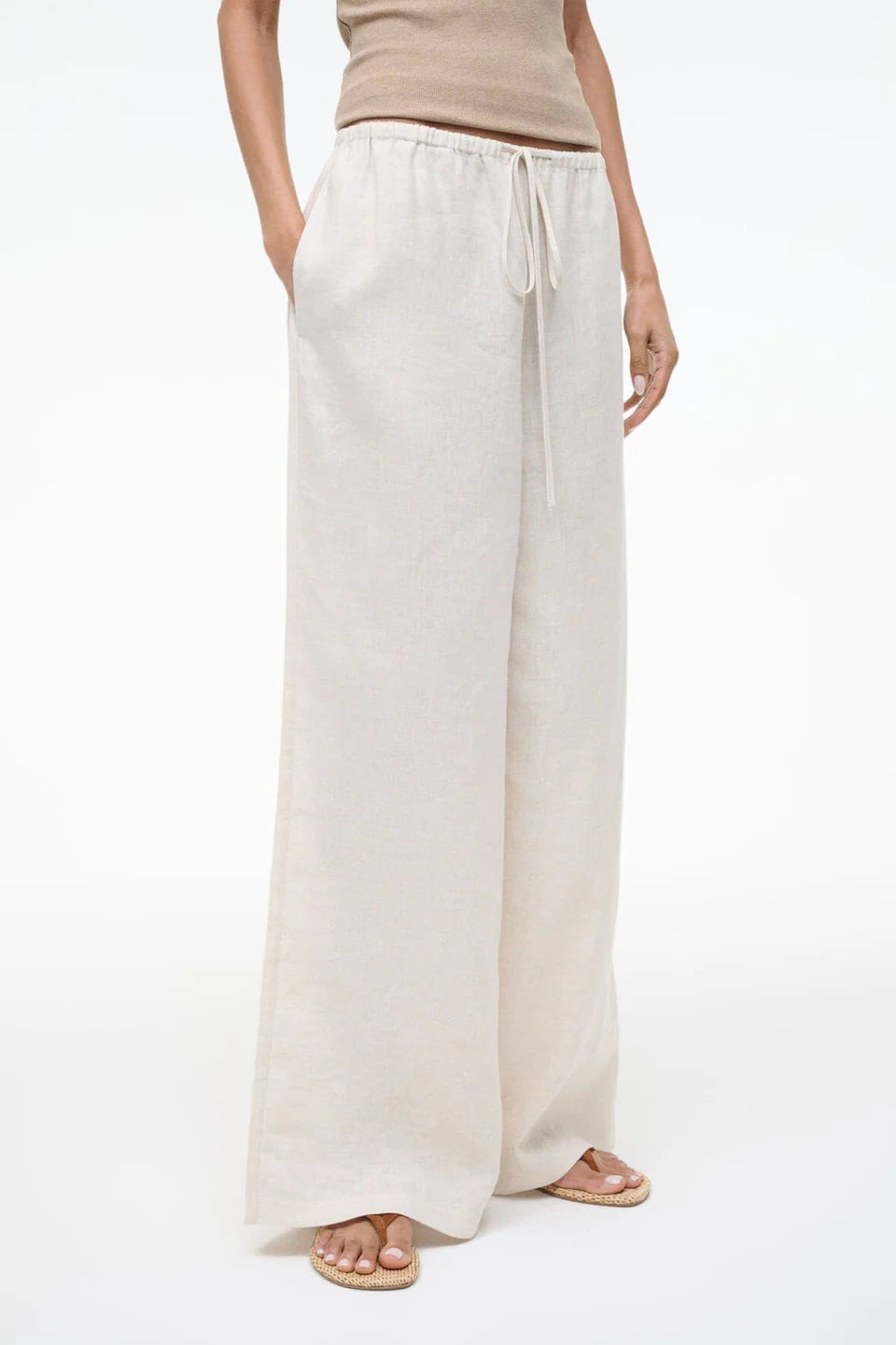 Person wearing white wide-leg pants on a white background