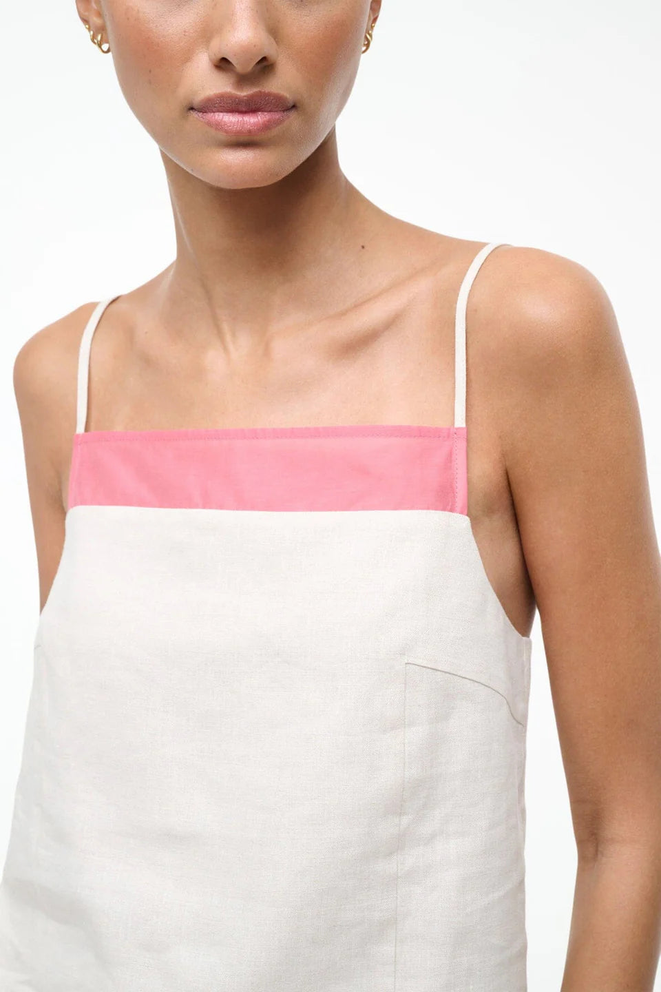 Woman wearing a white dress with pink straps against a white background