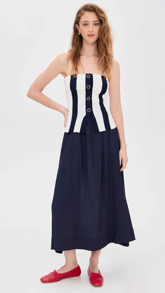 Woman wearing a strapless dress with a navy and white striped bodice on a white background