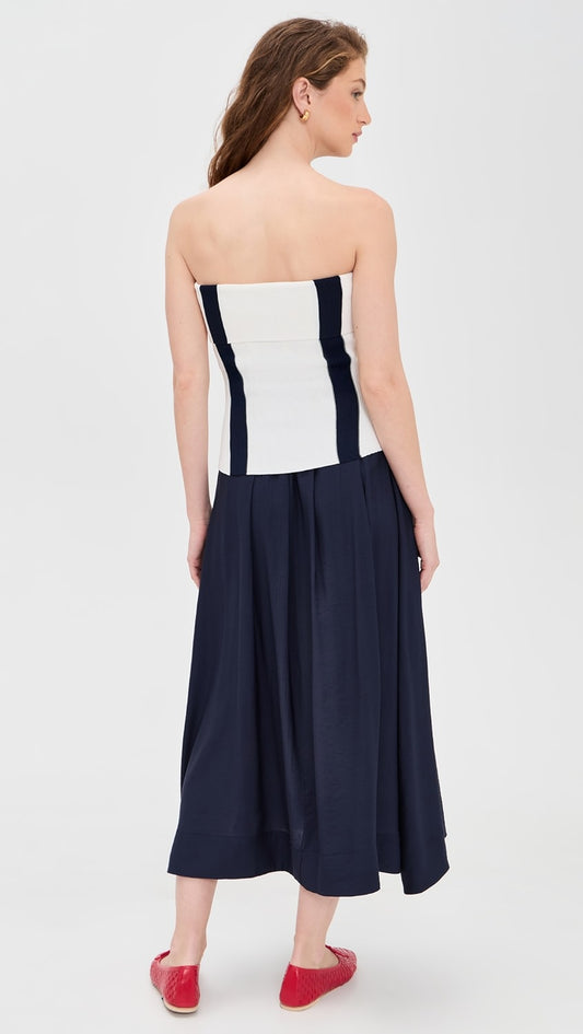 Woman wearing a strapless dress with white top and navy skirt on a white background