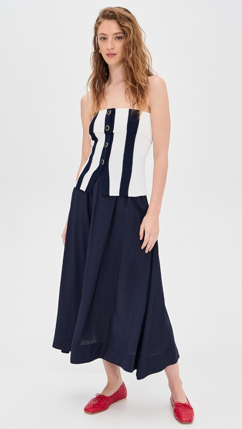 Woman wearing a strapless dress with a navy and white pattern on a white background