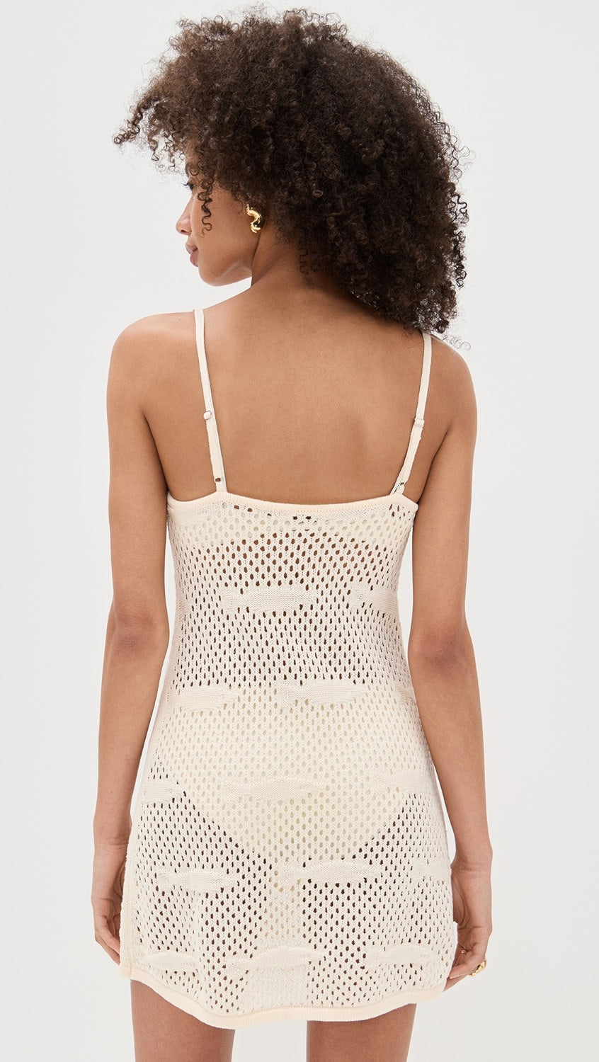 Woman wearing a beige crochet dress against a white background