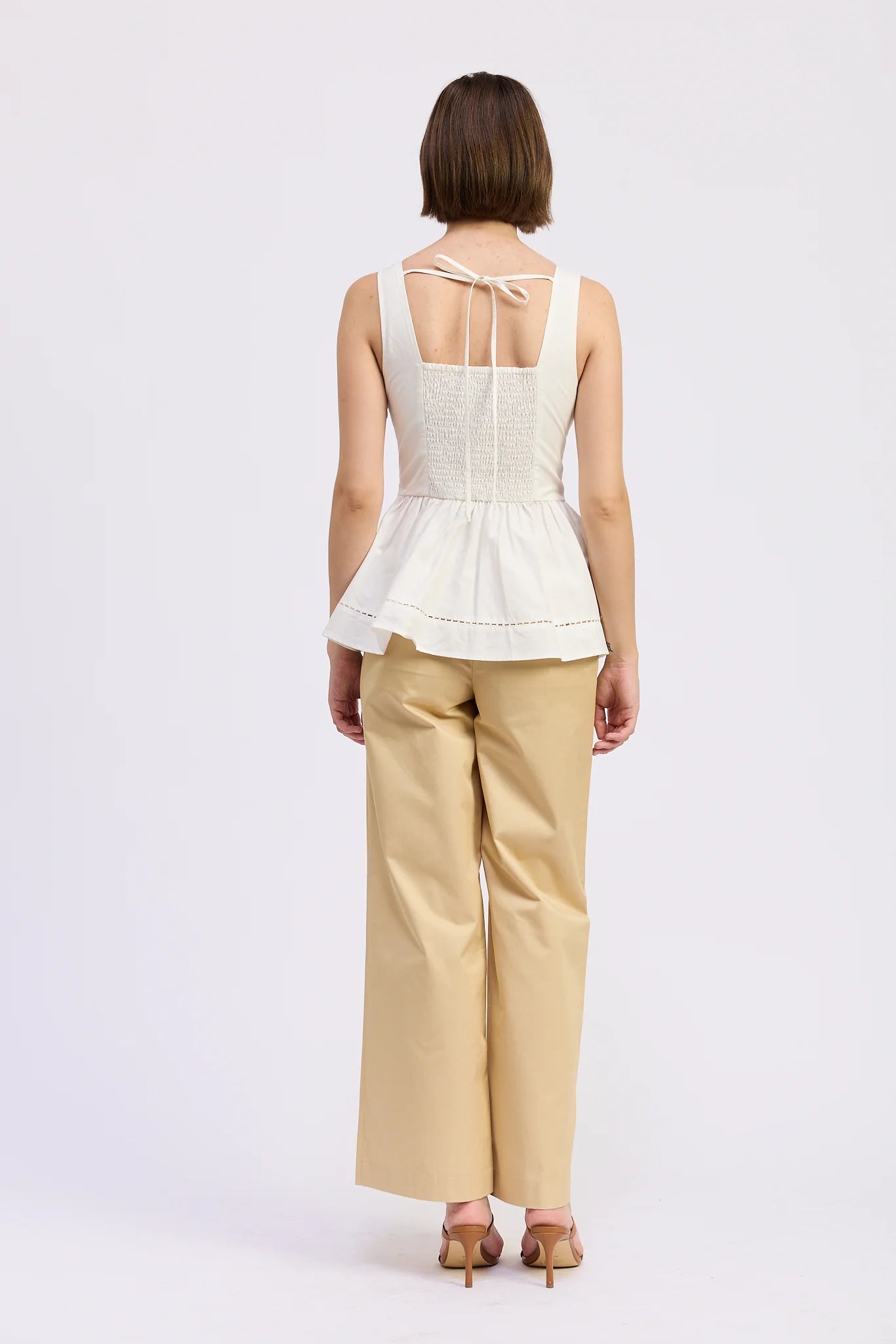 Woman wearing a white top and beige pants on a white background