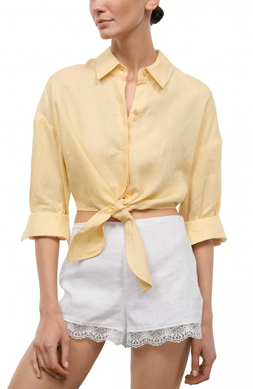 Woman wearing yellow button down top with tie front.