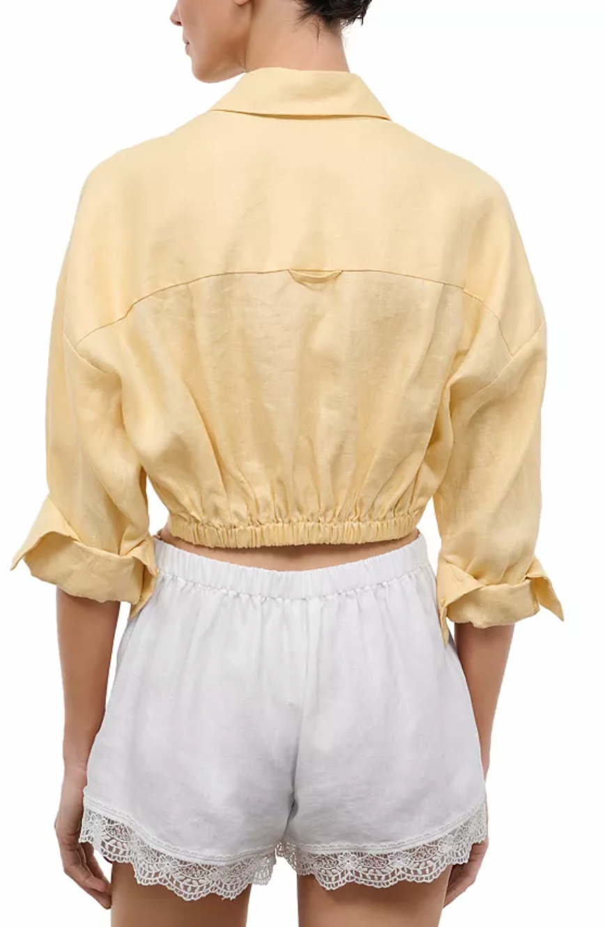 Back of woman wearing yellow cropped top and white shorts.