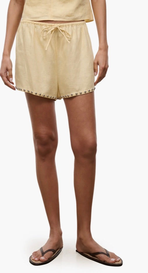 Beige shorts worn by a person on a white background