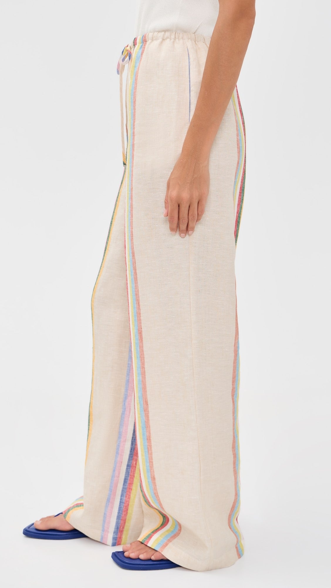 Beige wide-leg pants with rainbow side stripes worn by a person on a white background