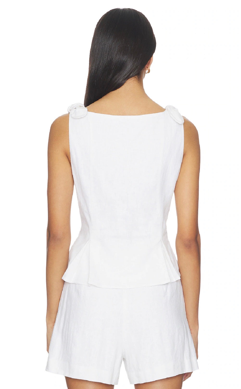 Woman wearing a white sleeveless top and shorts set on a white background