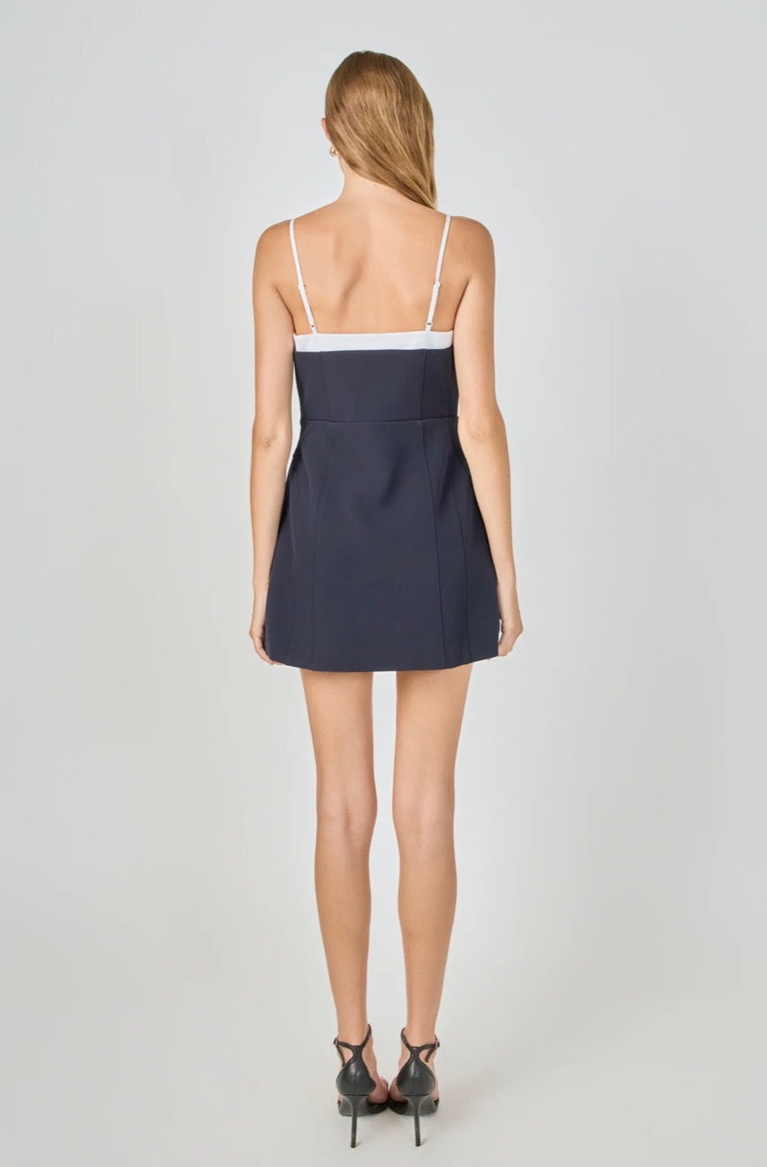 Woman wearing a navy blue dress with thin straps on a white background