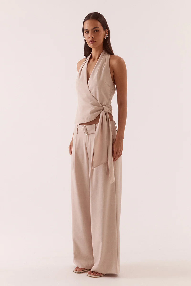 Woman wearing a beige halter neck top and wide-leg pants on a white background