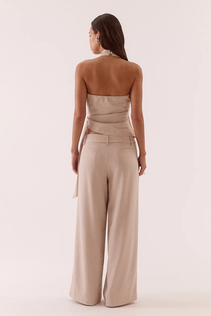Woman wearing a beige strapless jumpsuit on a plain background