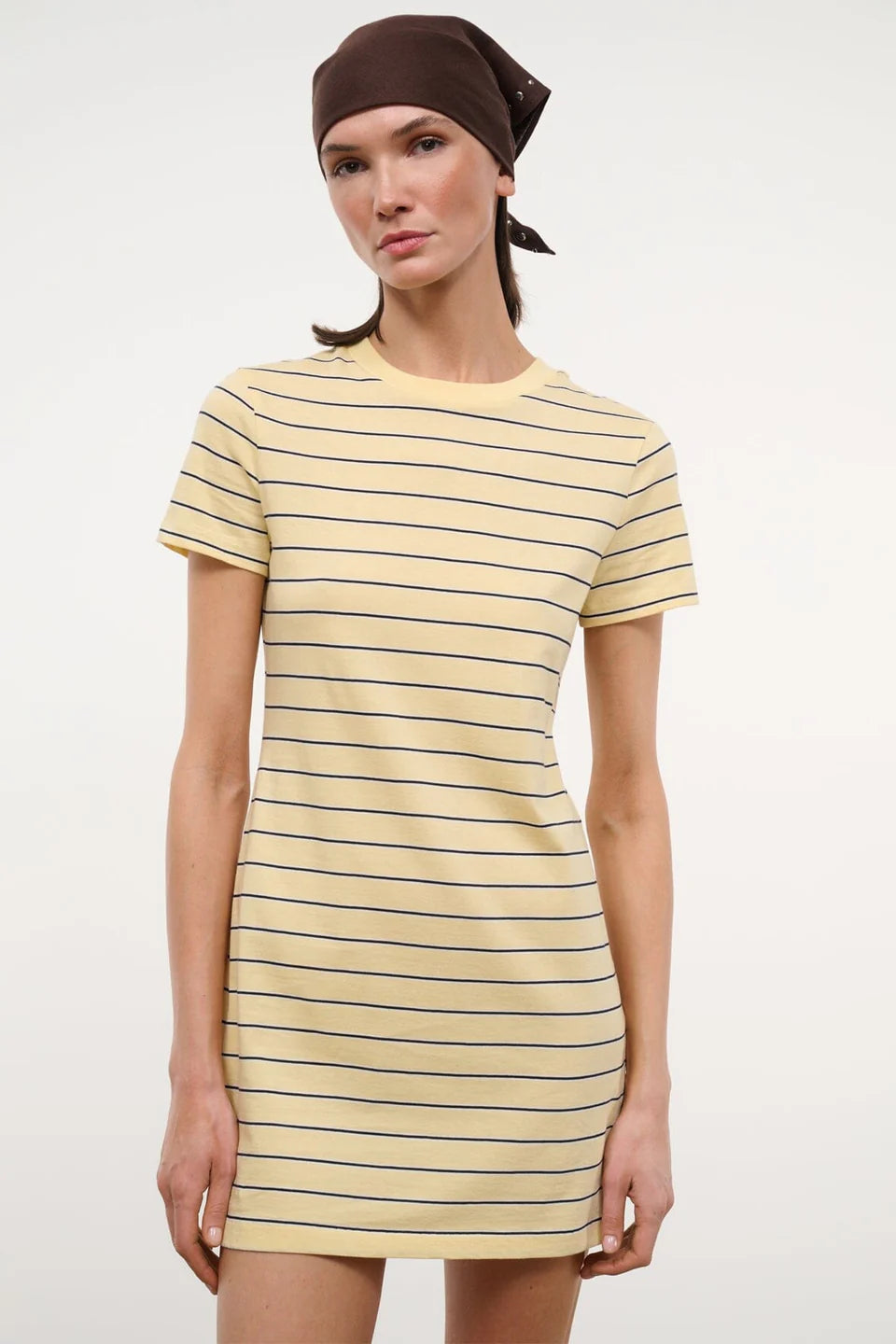 Woman wearing a yellow and black striped dress against a white background