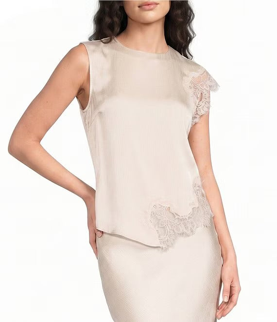 A woman wearing a sleeveless beige top with sheer lace flutter sleeves and matching lace trim at the hem, paired with a textured beige skirt, against a plain white background.