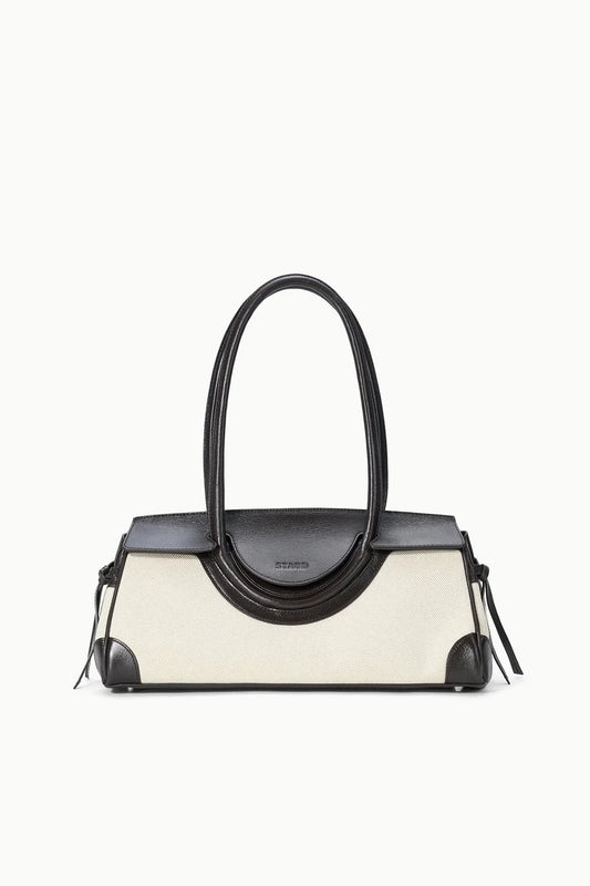 Handbag with black top handle and cream body on a white background