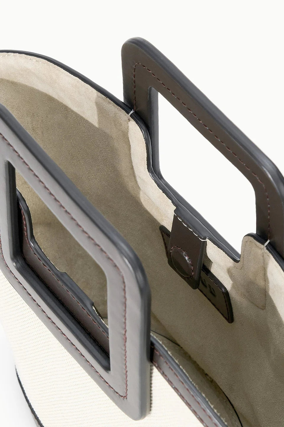 Close-up of a beige leather bag with a dark brown handle on a white background