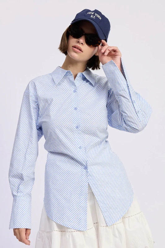 Person wearing a blue and white striped shirt with a navy cap and sunglasses on a light gray background