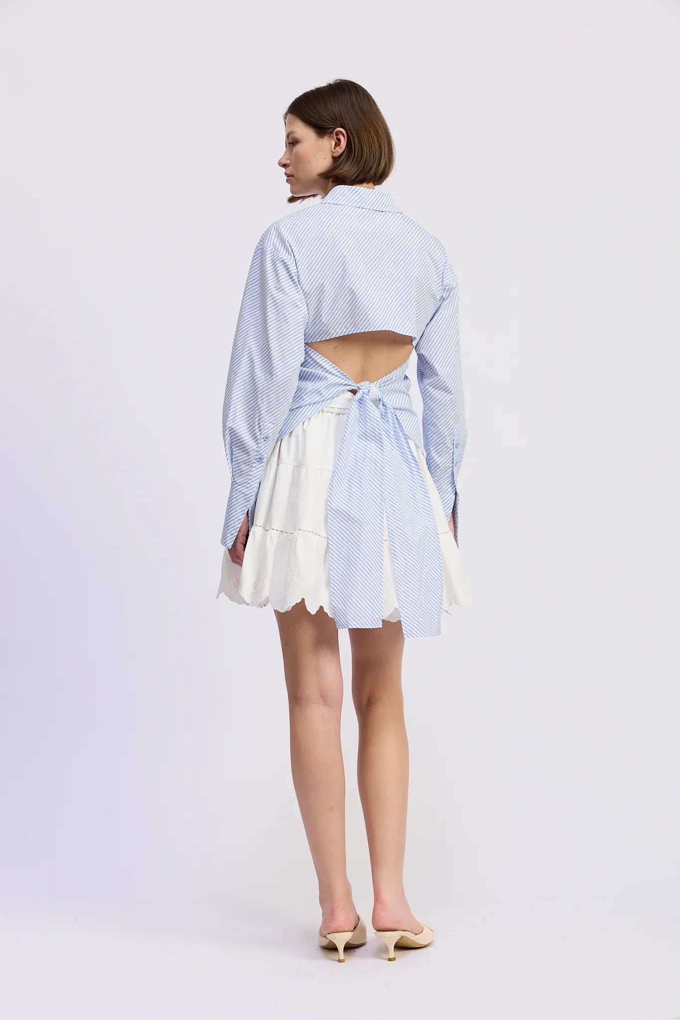 Woman wearing a light blue open-front shirt with a white skirt on a white background